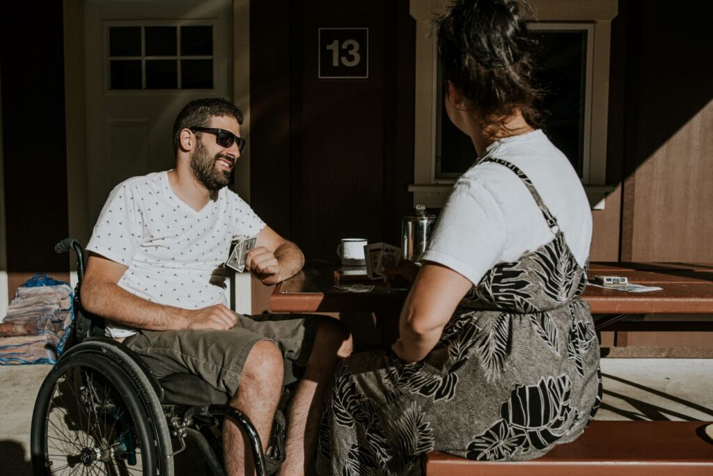 a man and woman playing cards at a picnic table