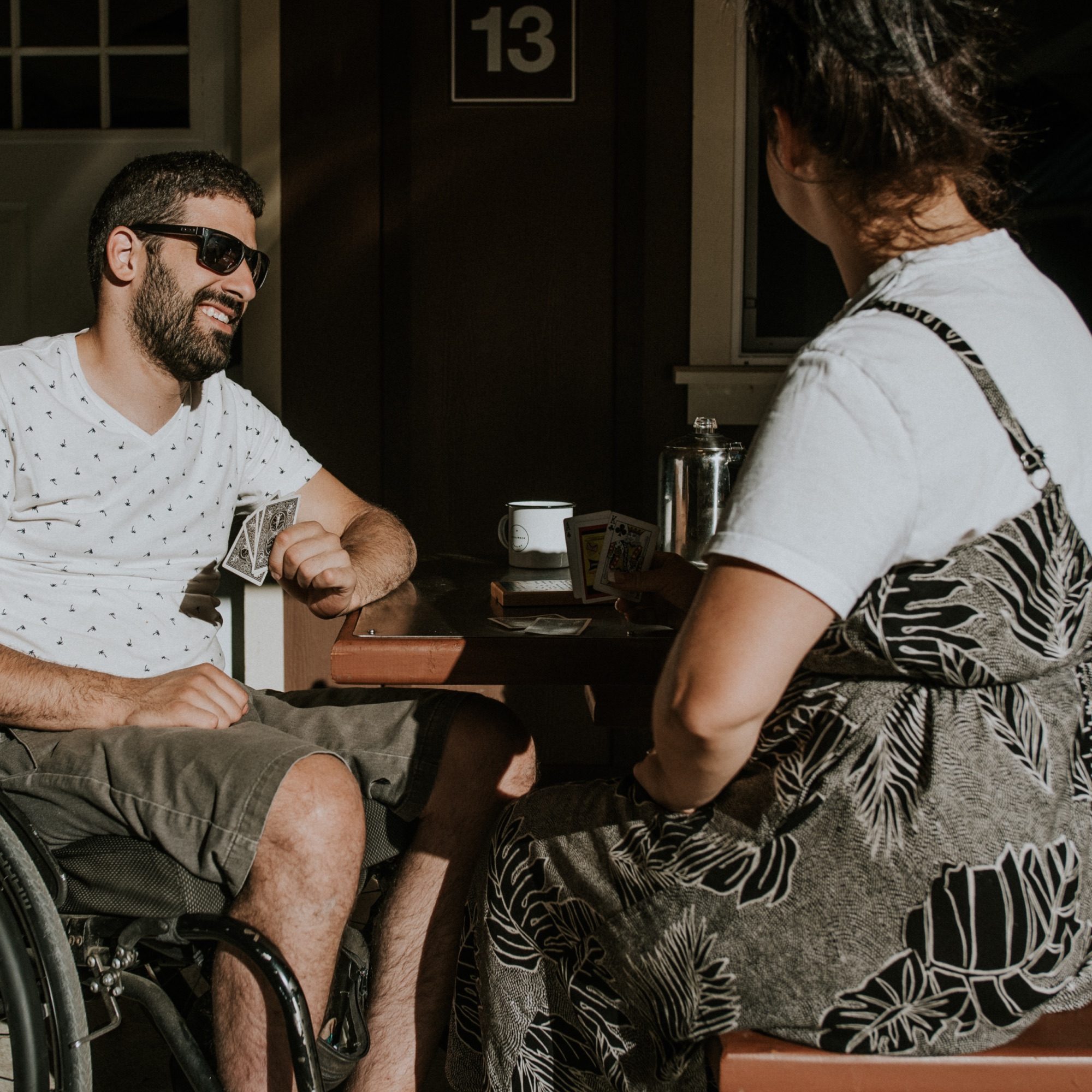 a man and woman playing cards at a picnic table