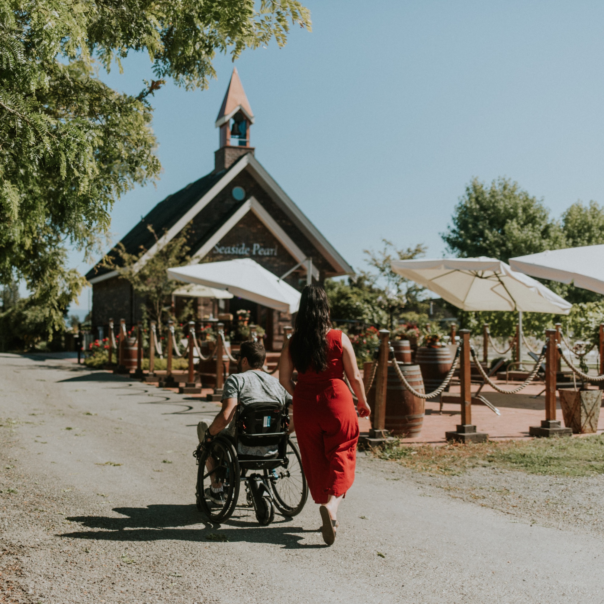 a woman and man in a wheelchair on a path leading up to a winery