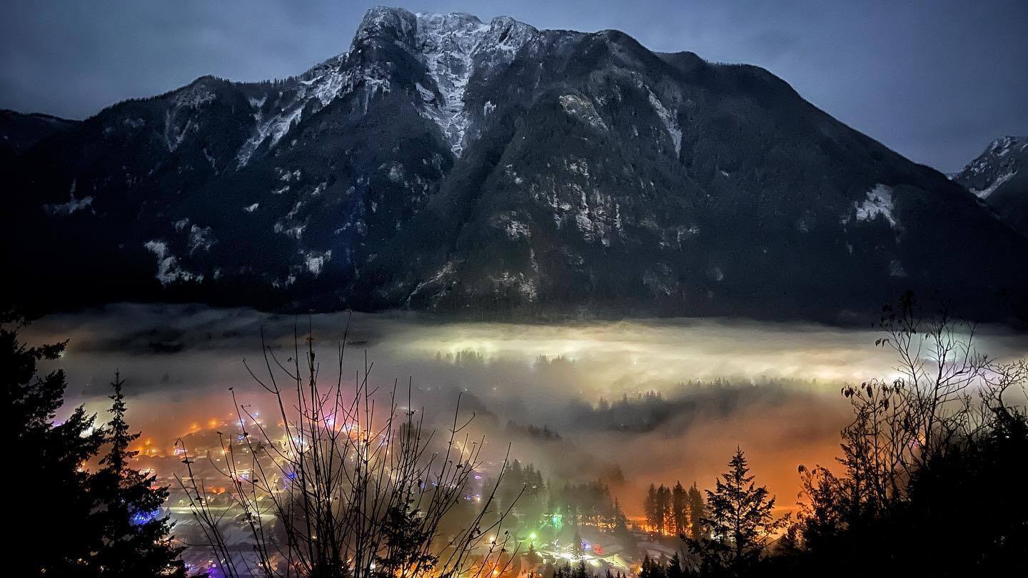 City shot aerial showing mountain and colourful lights