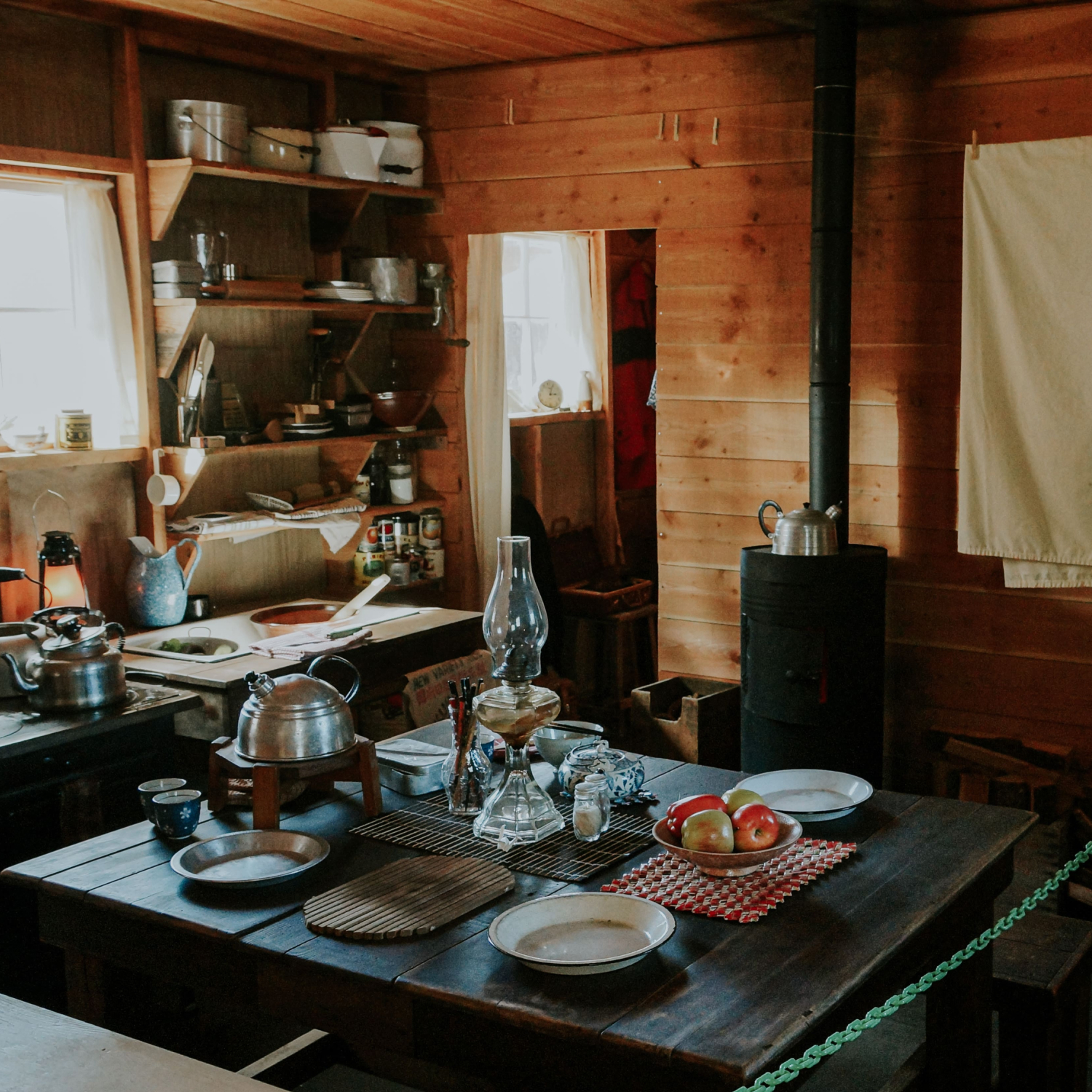 A museum display of a kitchen with a wooden table and four chairs arranged neatly.