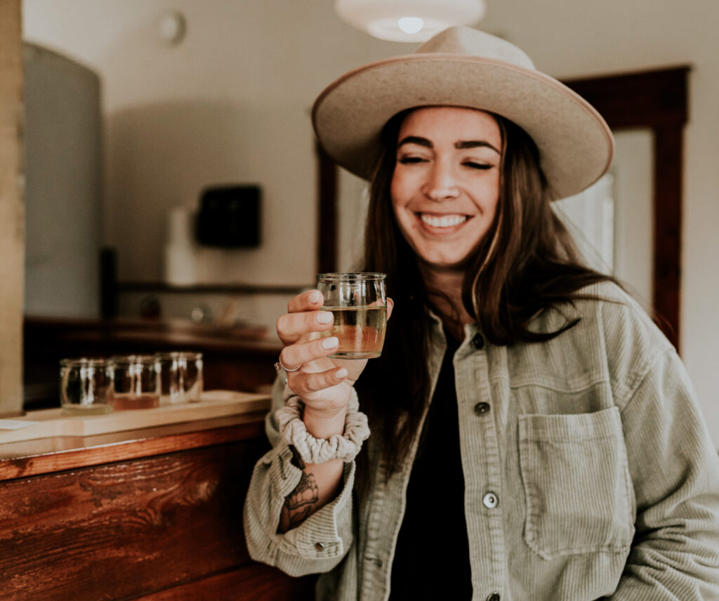 A woman holding a glass of cider at Cedar Cider's tasting room.
