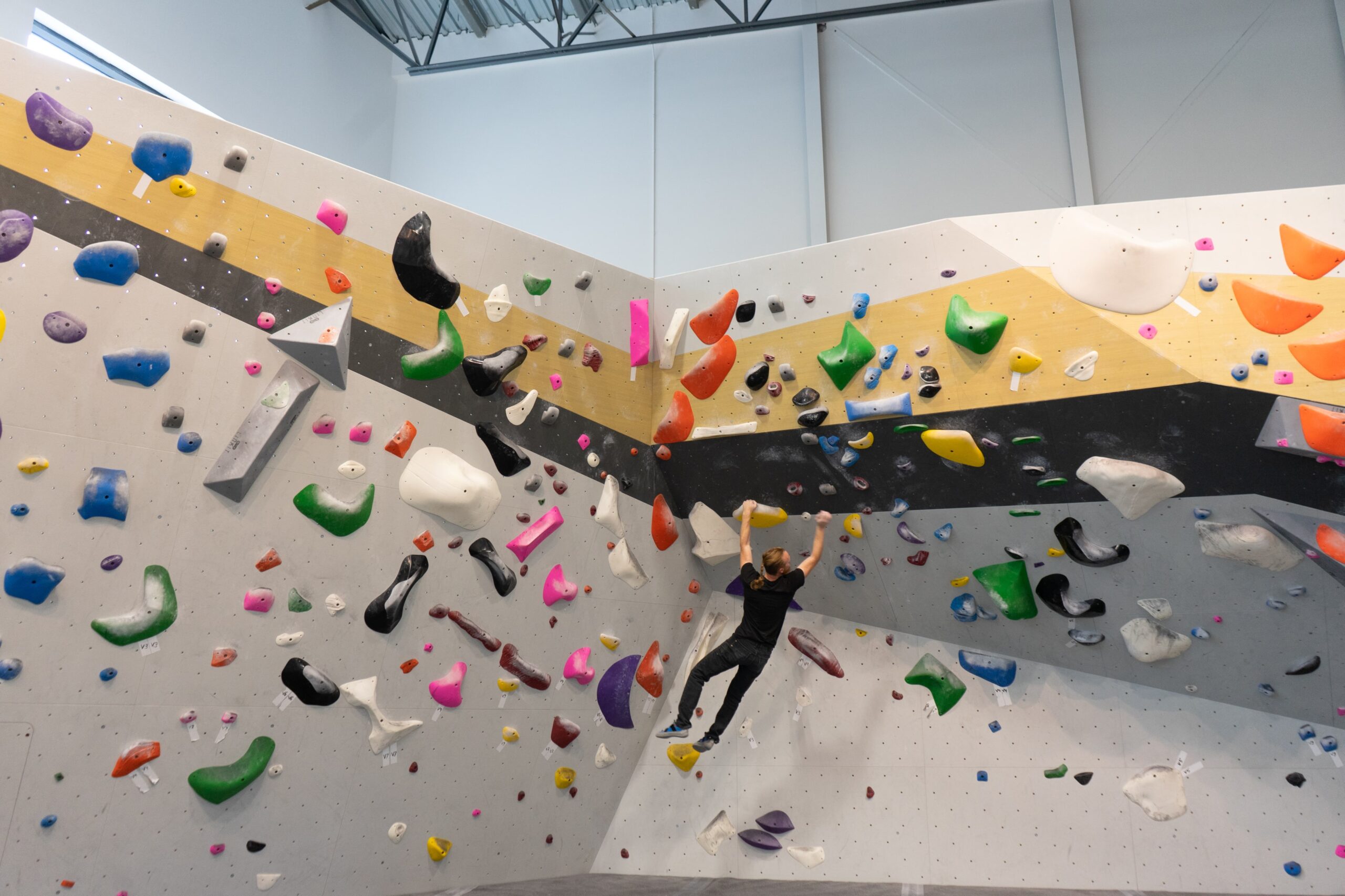 A person scaling a rock wall in an indoor climbing gym, demonstrating strength and determination.