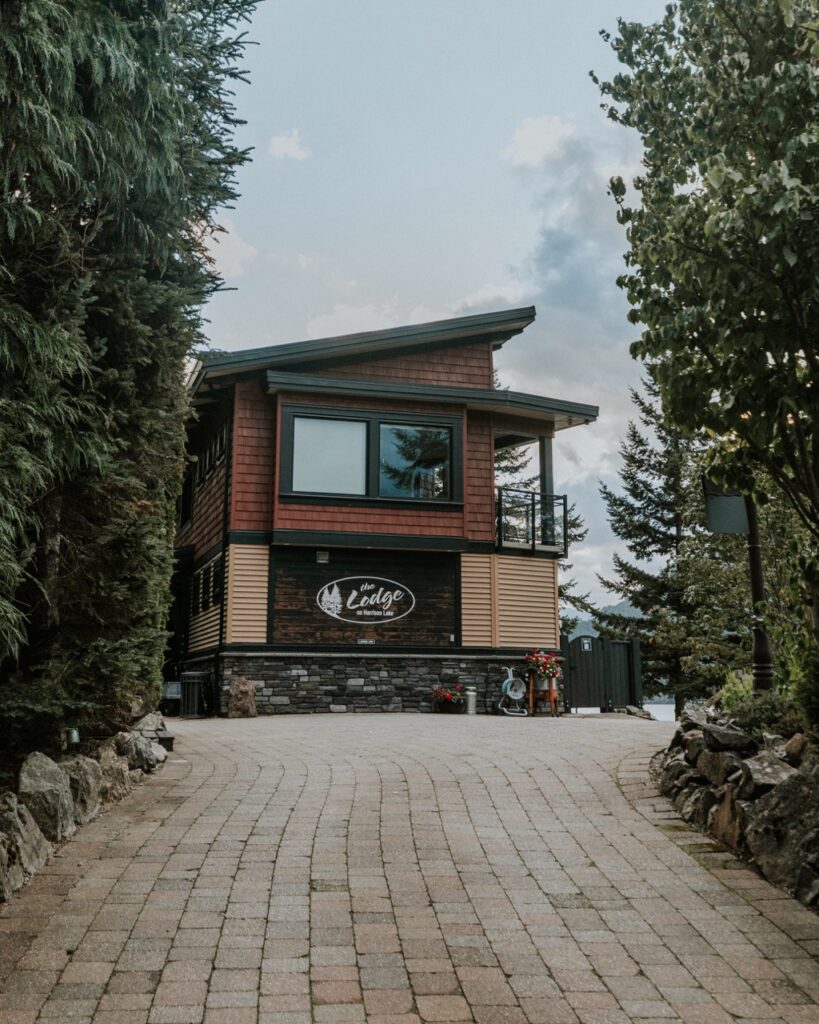 A pathway leading up to a brown building, with a sign that says "The Lodge"