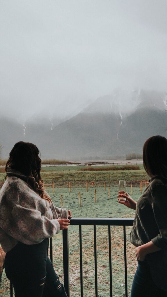 Two women standing on a deck, looking at the fog and mountains