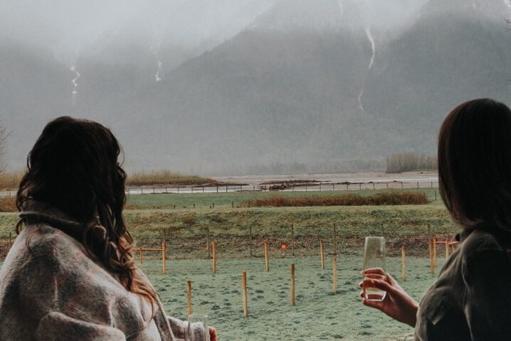 Two women standing on a deck, looking at the fog and mountains
