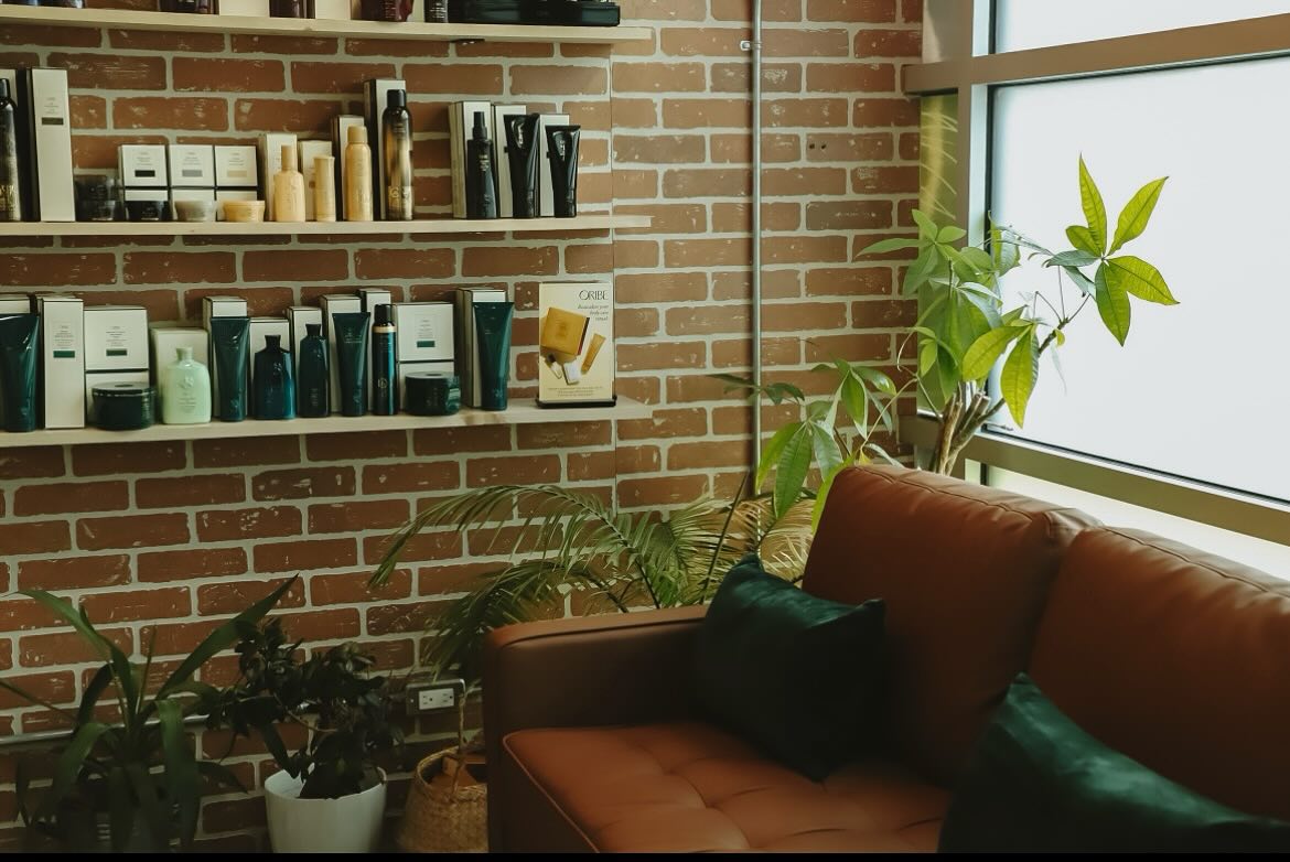 A sofa against a windowsill, with shelves on the wall next to it lined with spa products.