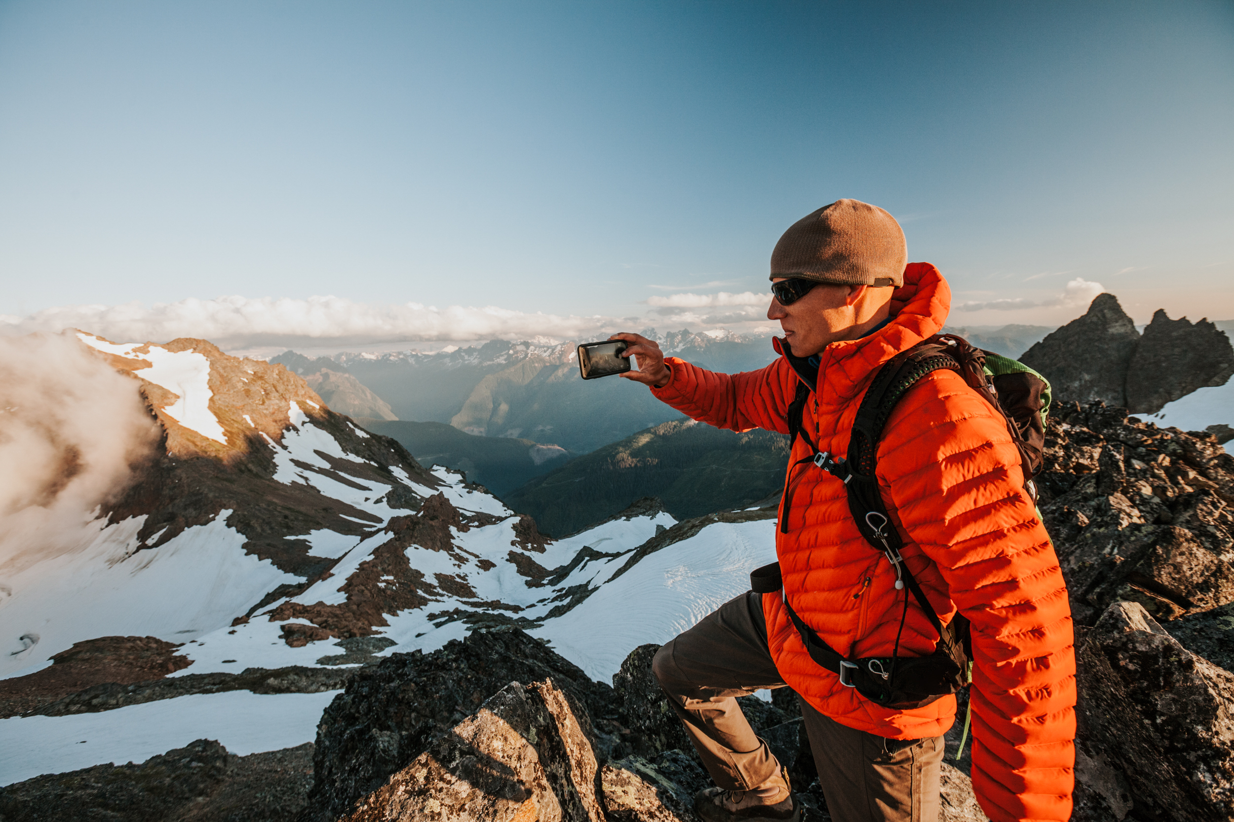 A Climber Using His Smart Phone To Take A Picture Of The View From A Rocky Summit