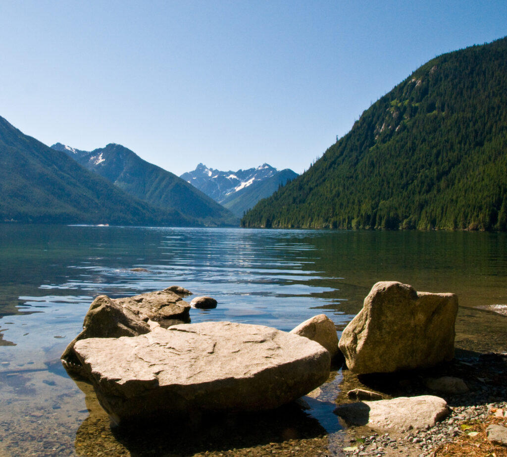 rocks at the shore of a lake with mountains in the background