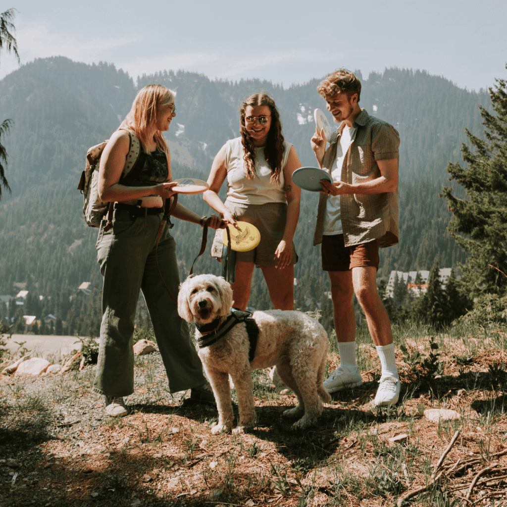 3 people and a dog get ready to play disc golf