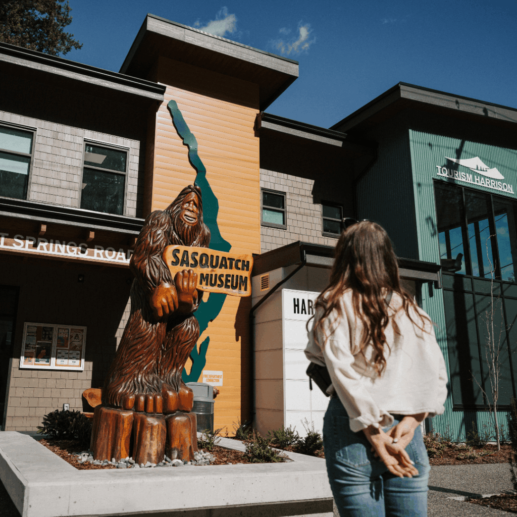 a woman looks at a wooden sasquatch carving