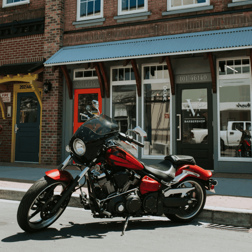 A red and black motorcycle in front of stores