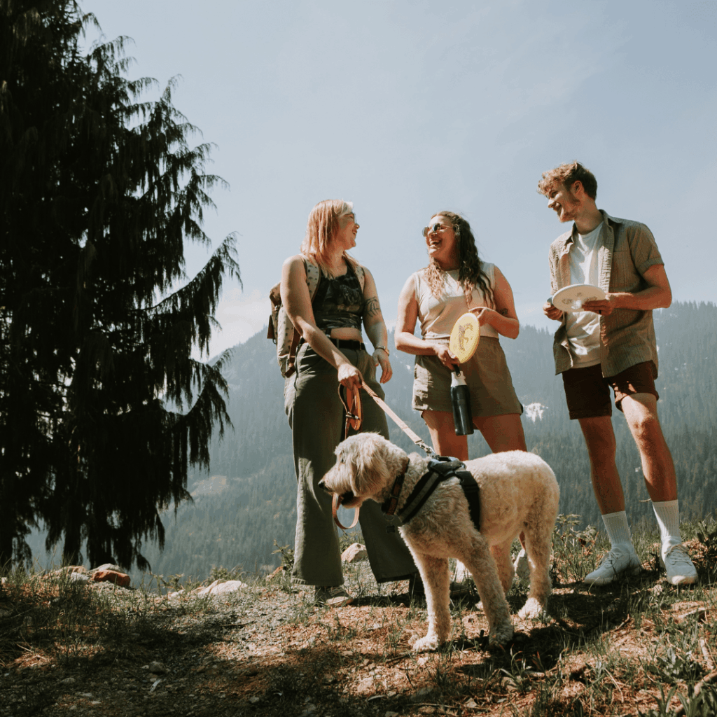 Three people and a dog, the people holding a frisbee in their hands