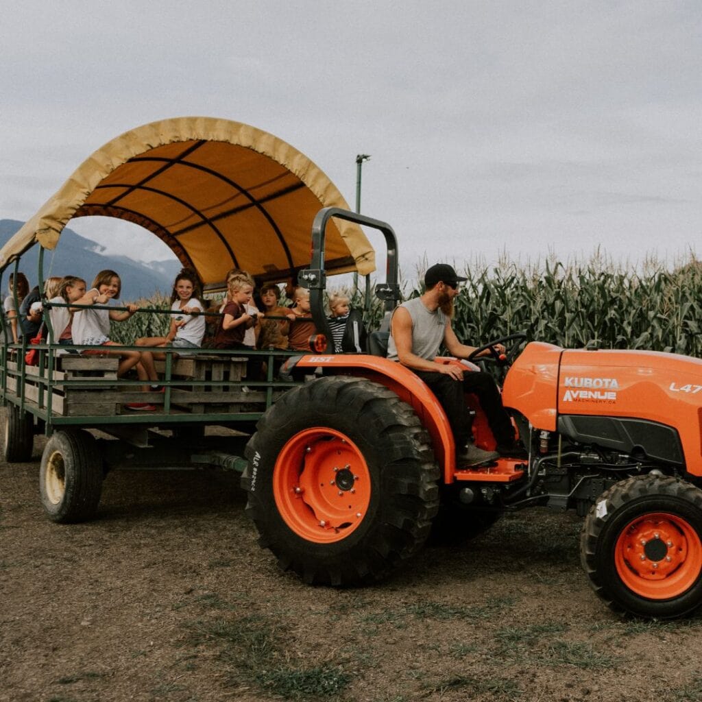 an orange tractor pulling a wagon full of children