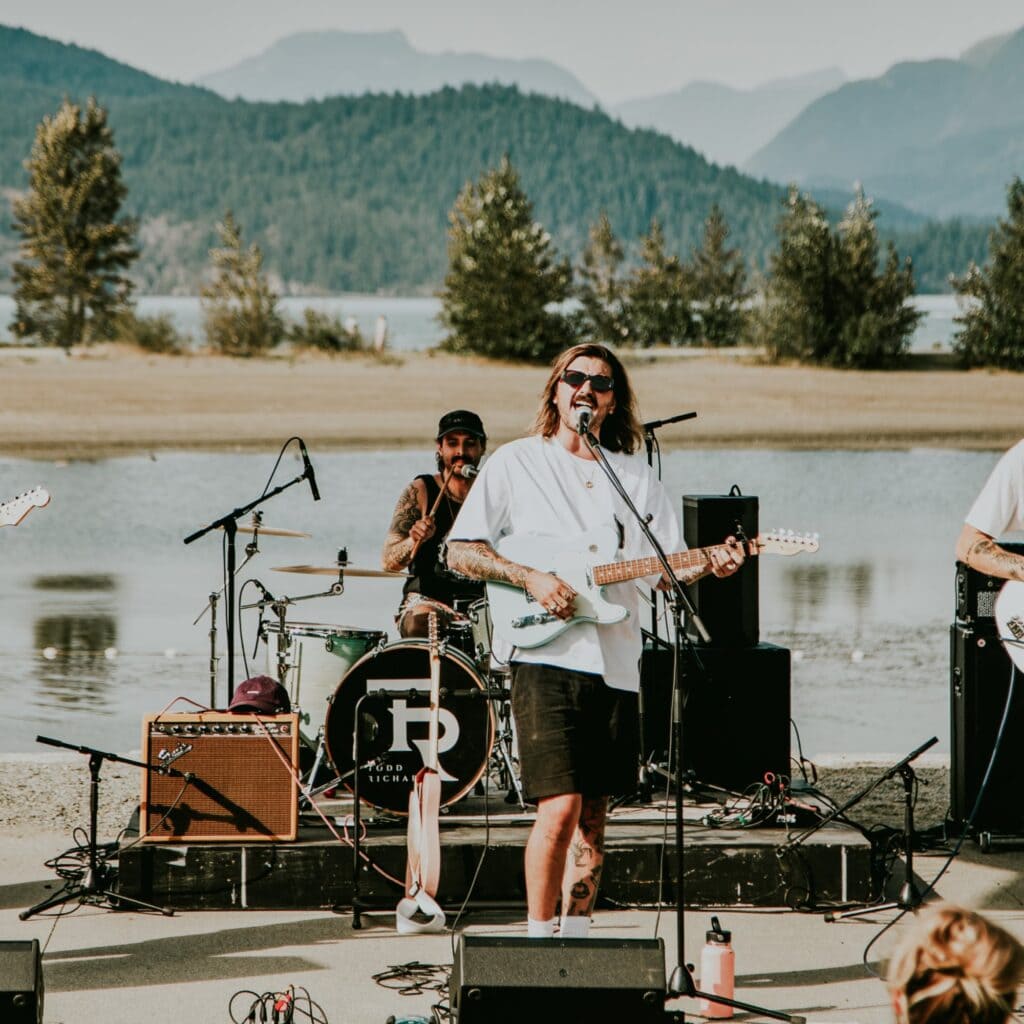 A band performs with a lake and mountains in the background