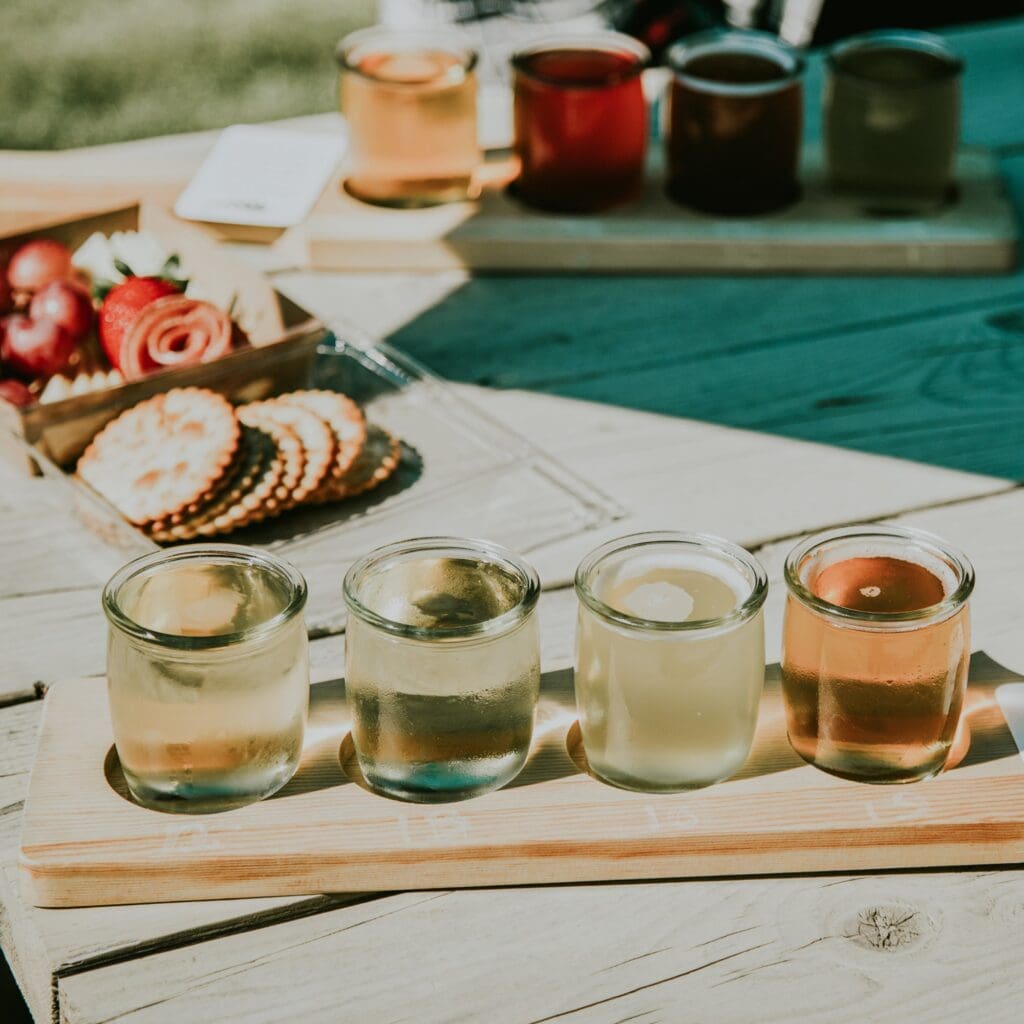 a flight of ciders sitting on an outdoor table
