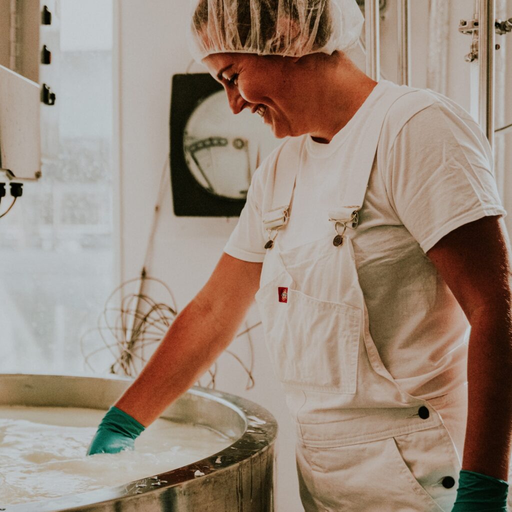 a person with a food safety cap on makes cheese