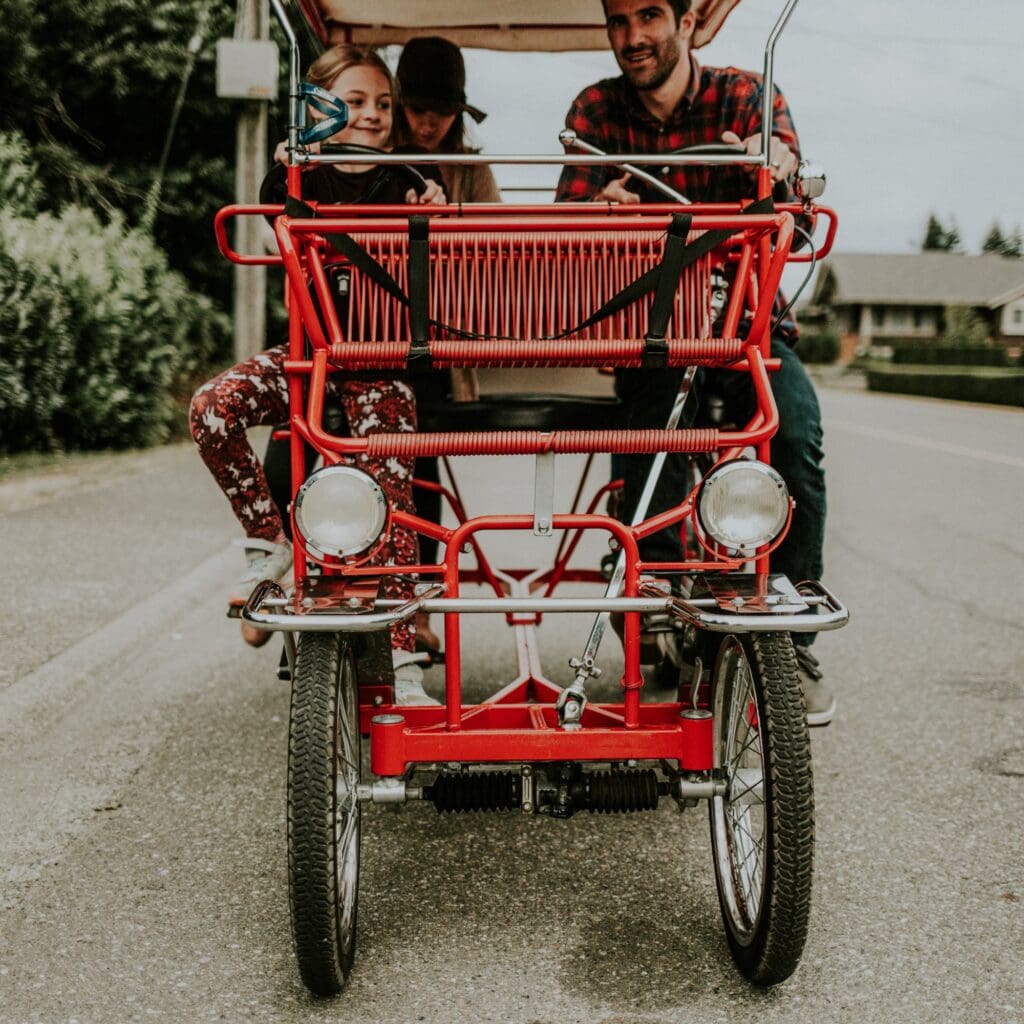 A family drives a red pedal bike