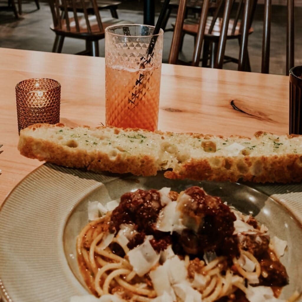 A plate of pasta with a drink in the background
