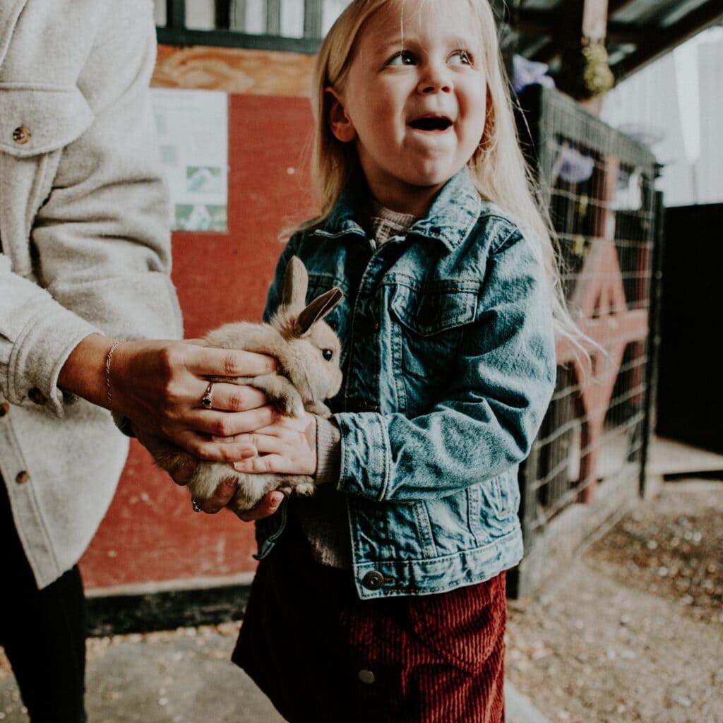A young child holds a baby bunny