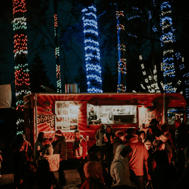People crowded in front of a food truck with christmas lights
