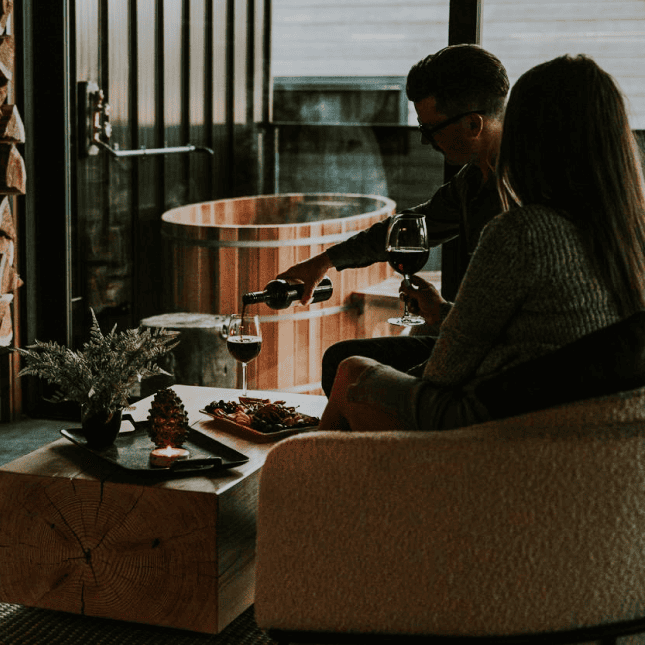 People hanging out around a table pouring a glass of wine