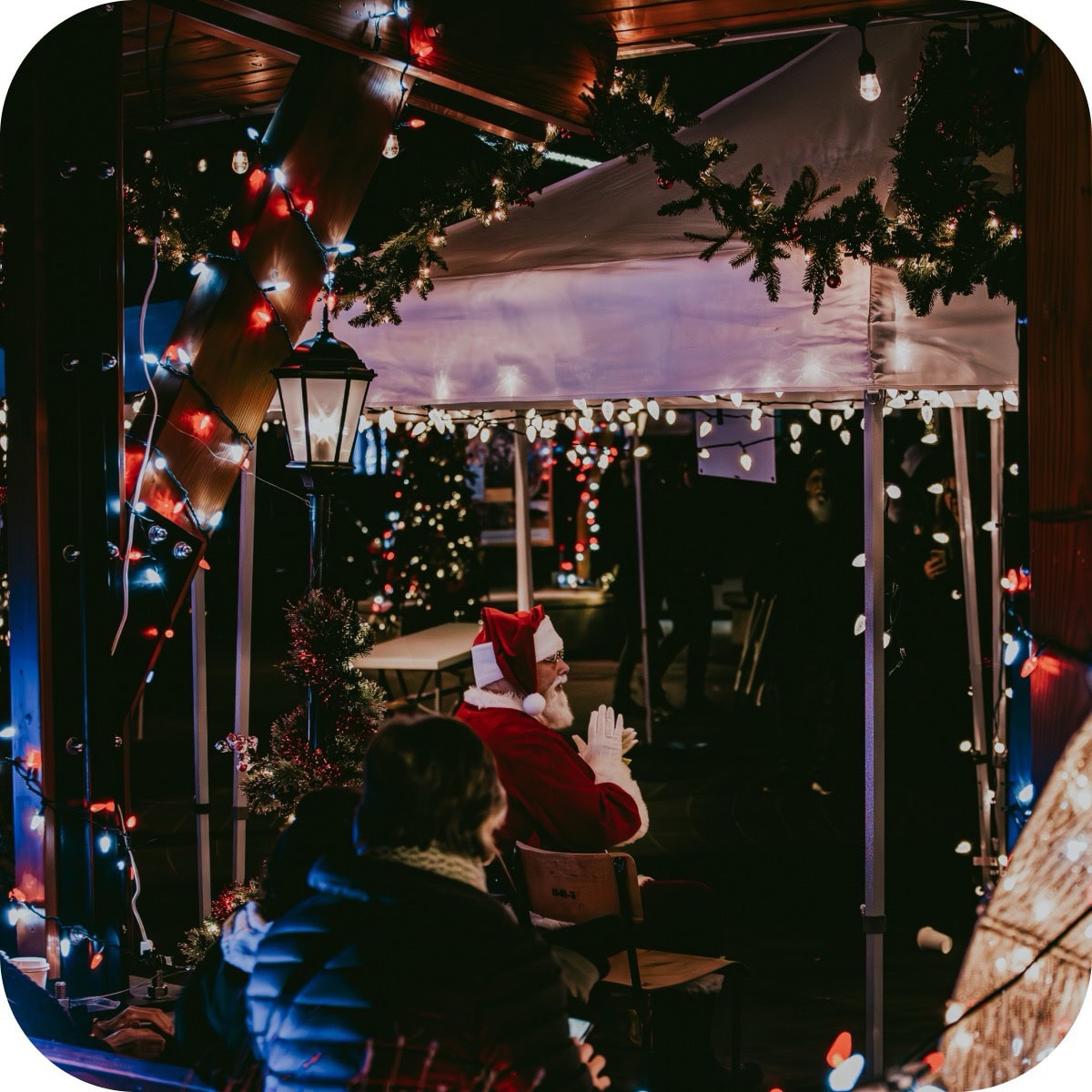 Santa sitting in a display surrounded by lights