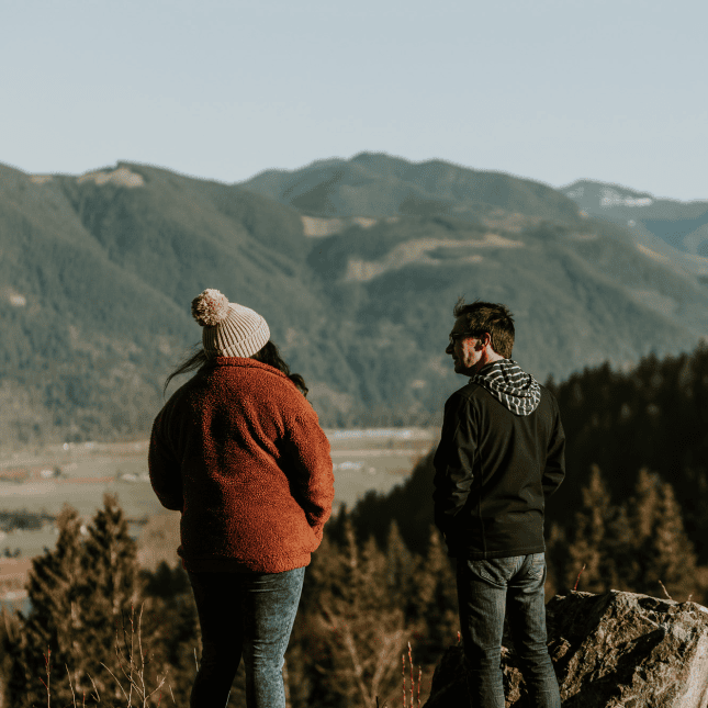 Two people standing on mountain looking out 