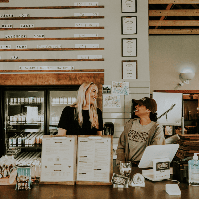 Two woman laughing behind a counter working 