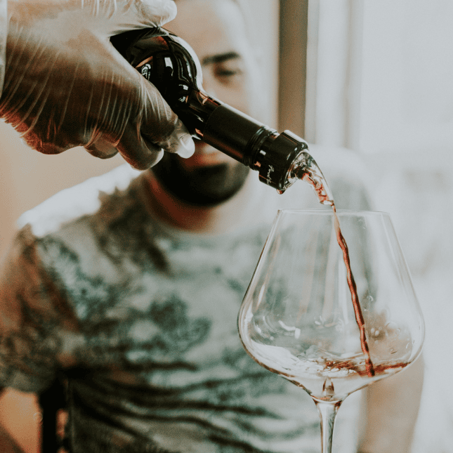 Man getting glass of wine poured for him 