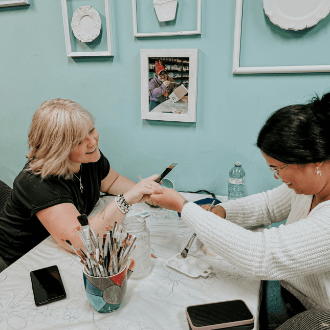 Two people sitting at a table creating art 