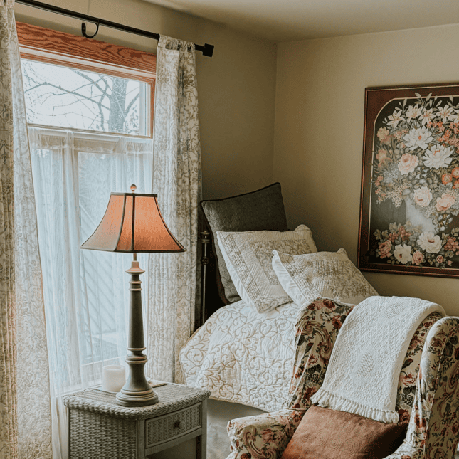 Room set up with made bed and lamp on side table