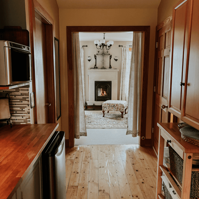 Inside of a hallway in a house with a fireplace at the end 
