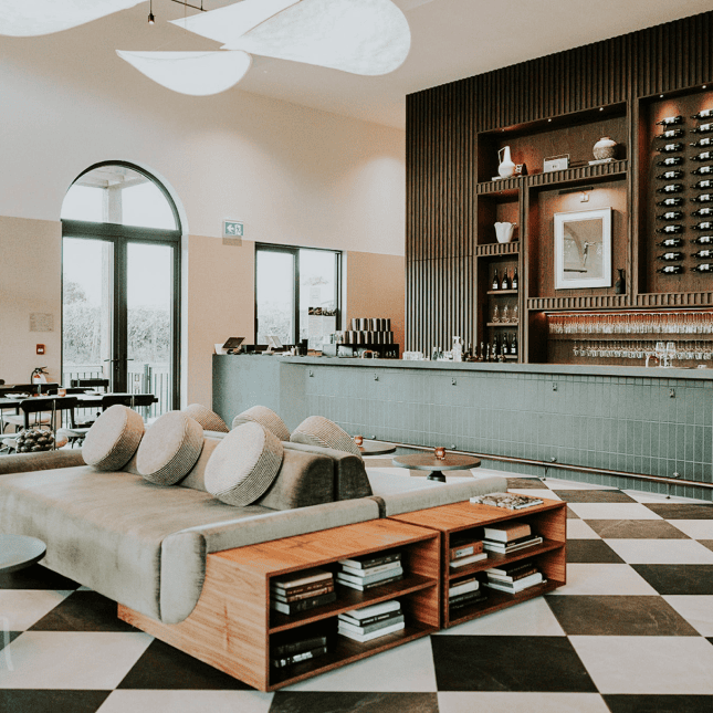 Bright, modern lounge area with neutral furniture, wooden accents, and large arched windows.