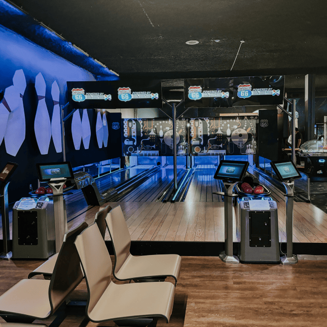 Indoor bowling alley with glowing blue lights and multiple lanes.