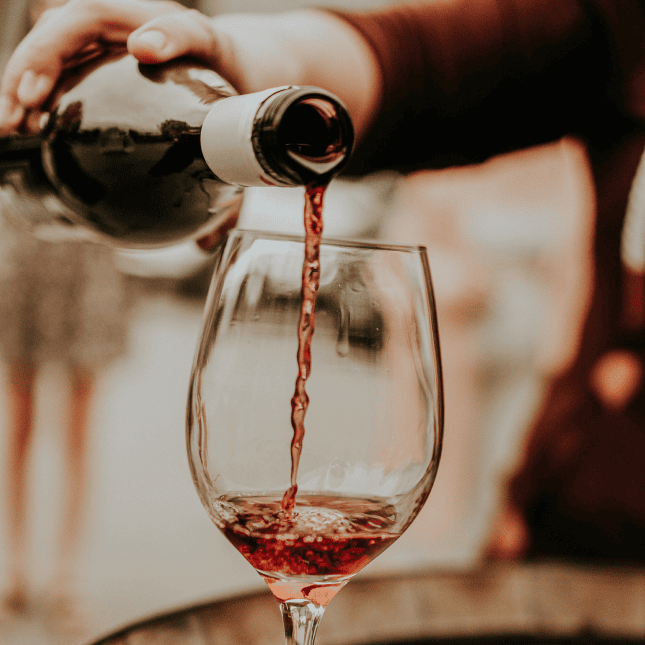 Red wine being poured into a glass during a tasting.