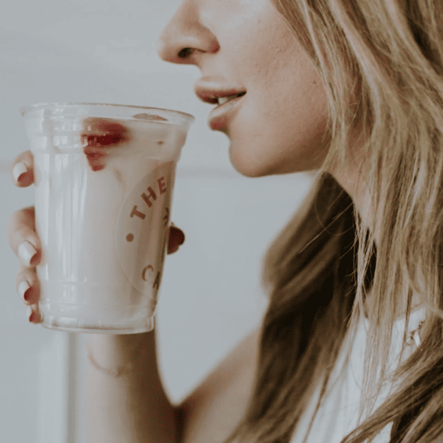 Person sipping a drink from a branded café cup.