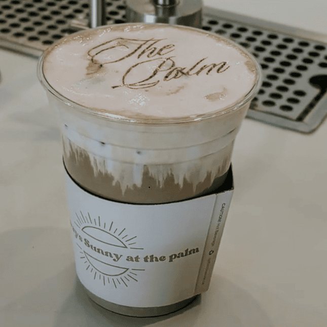 Iced specialty coffee topped with foam in a clear branded cup.