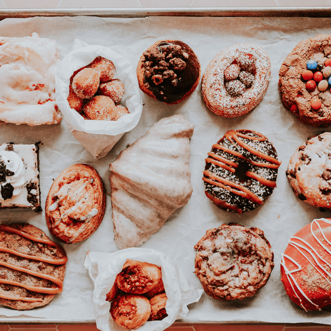 Assortment of decorated donuts arranged in neat rows.