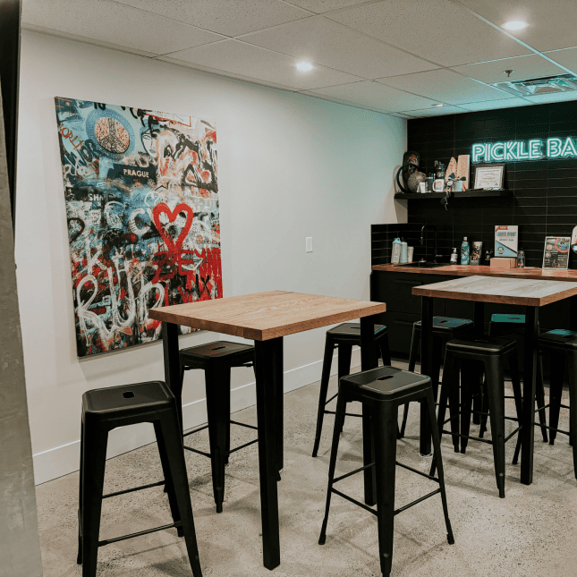 Empty room with high-top tables and a colourful piece of art on the wall