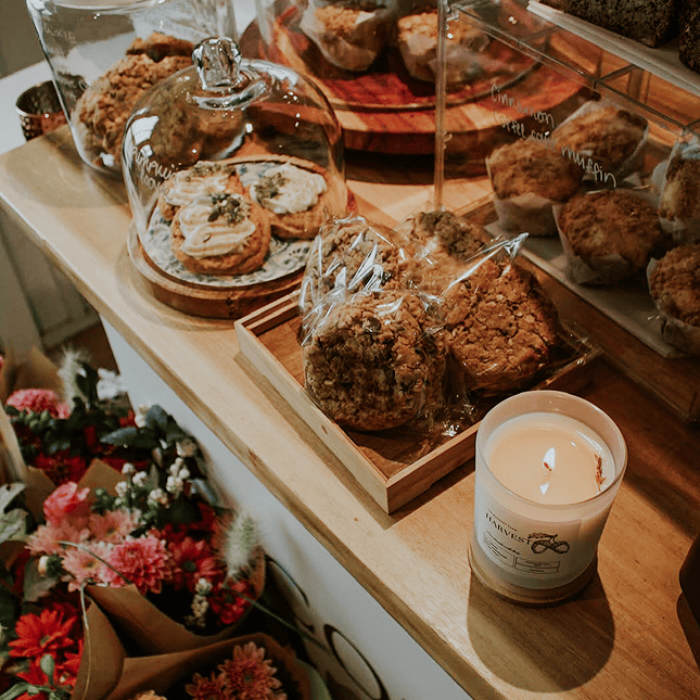 Assorted baked goods displayed on a wooden board with candles and floral accents.