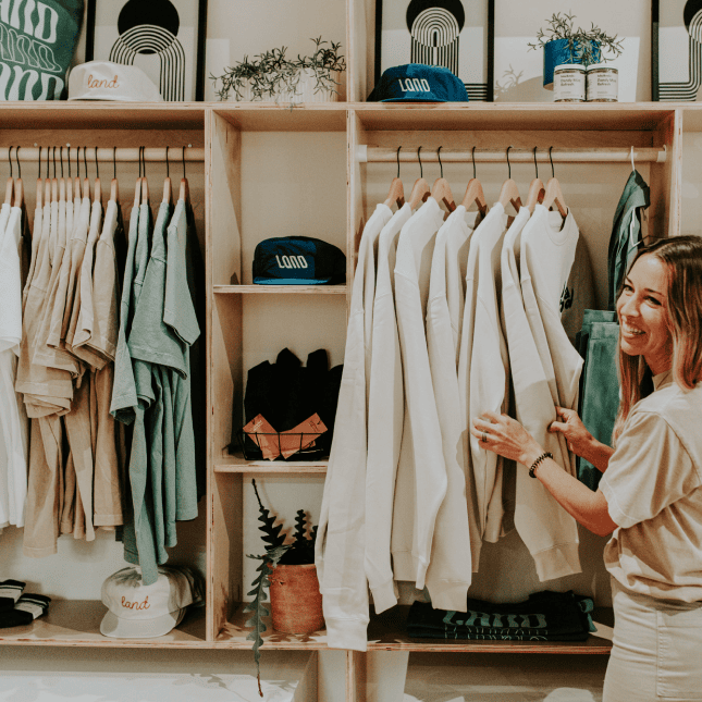 A cozy studio with clothing racks, folded apparel, and warm neutral décor.