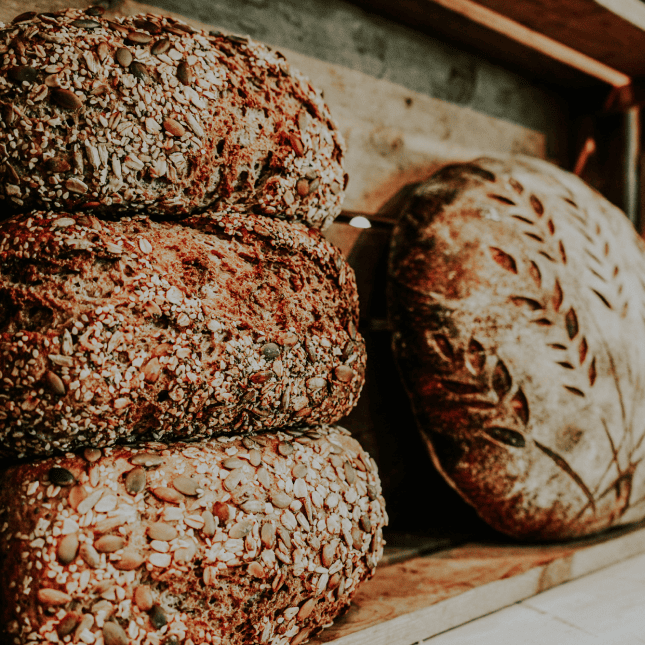 Close-up of rustic, seeded bread loaves stacked together.