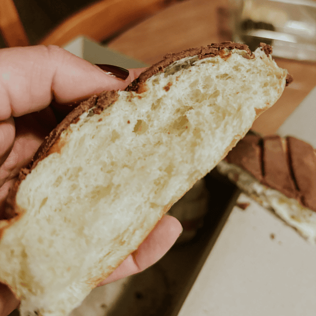 Hand holding a sliced loaf of bread, showing the soft interior crumb.