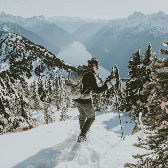 A person snowshoeing together on a scenic winter trail overlooking mountains.