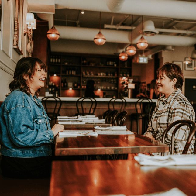 Café counter scene with staff preparing drinks and customers chatting.
