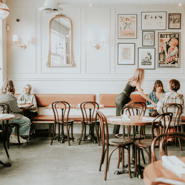 Bright café interior with wooden tables, chairs, and natural light.