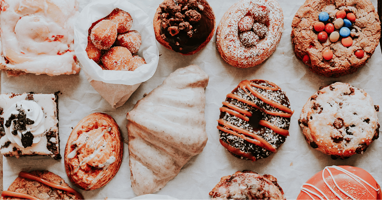 Assortment of decorated donuts arranged neatly on a light background.