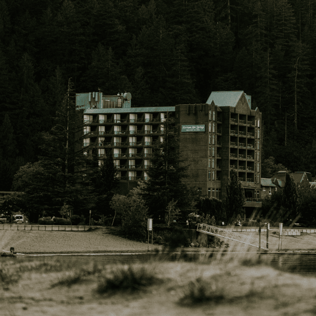 Exterior view of a multi-story resort surrounded by trees and mountains.