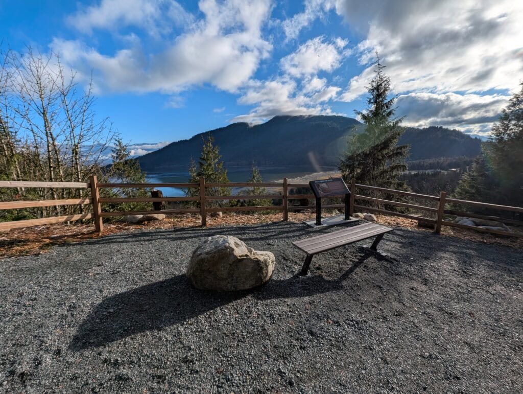 a viewpoint of mountains and a river, with a bench to enjoy the view